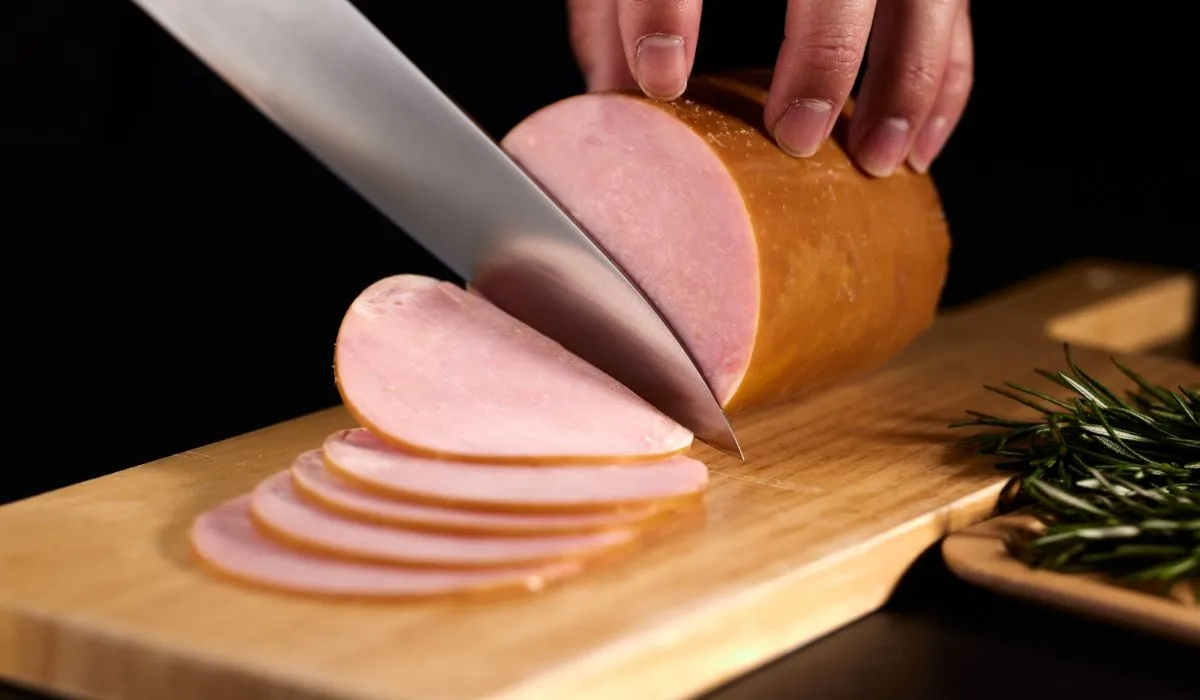 Woman preparing a turkey deli meat sandwich while breastfeeding